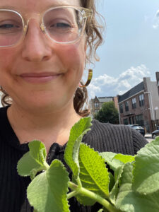 A former HVF apprentice holding a plant in NYC.